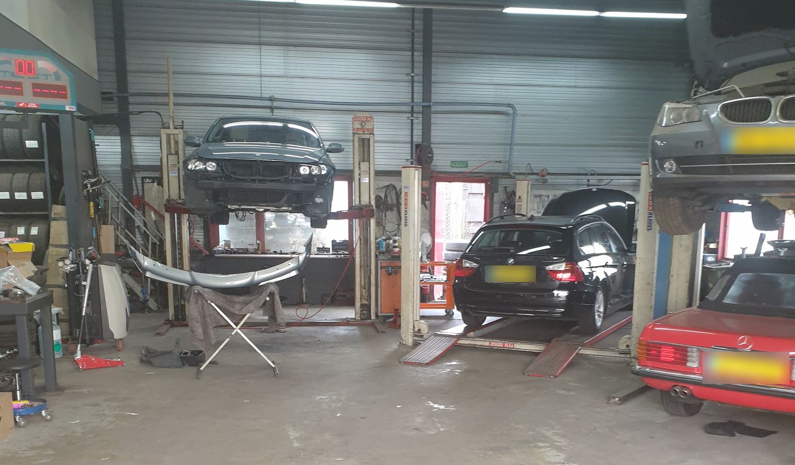De werkplaats van BVS: twee BMW's op de brug, een BMW Touring op de APK-plaat en een klassieke Mercedes SL